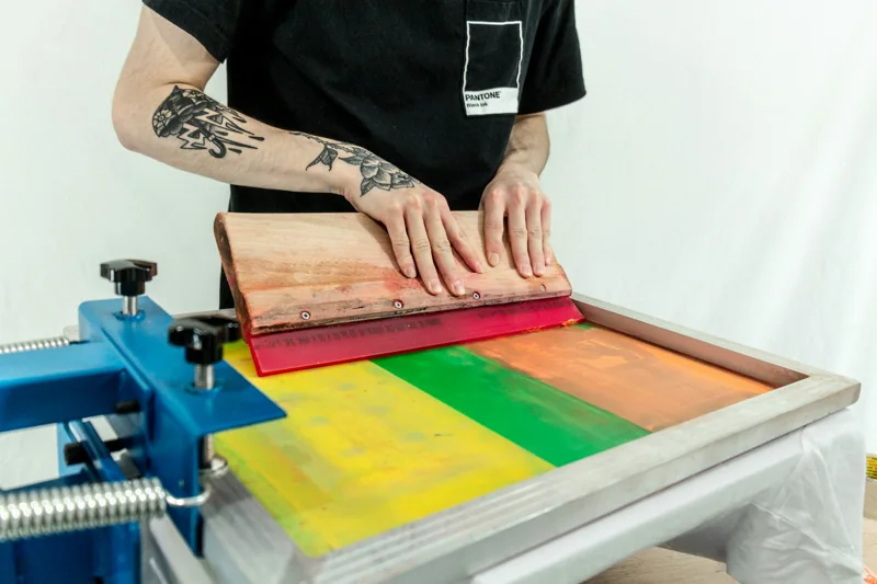 Ink being pulled across a screen in a garment printing press